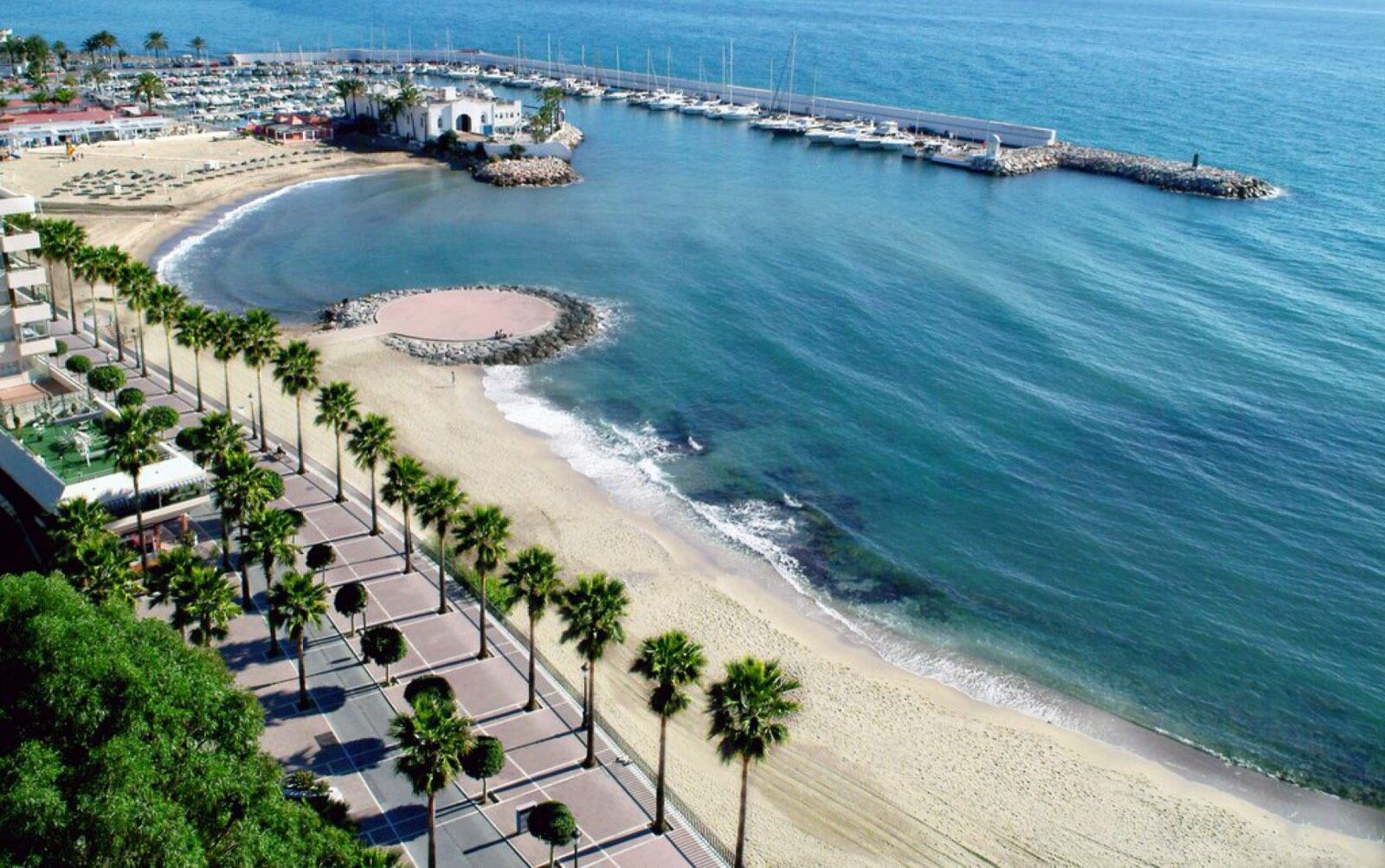 Playa del Faro and the Marbella marina promenade, lined with palms