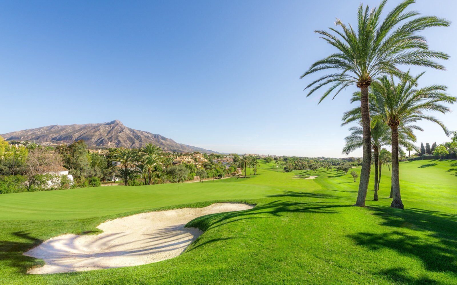 A fairway and bunker at Real Club de Golf Las Brisas, with La Concha mountain behind