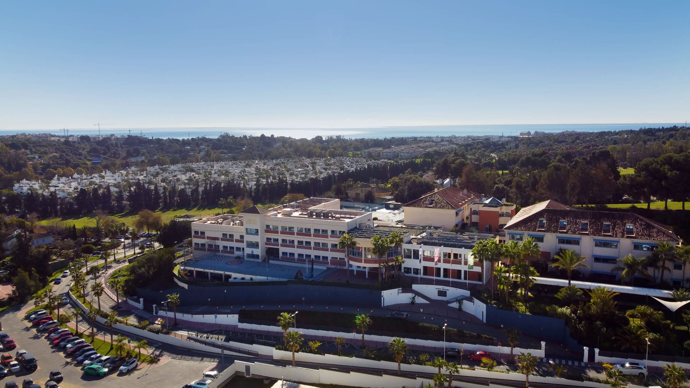 Aerial view of the Aloha College Marbella campus, with the coast behind it