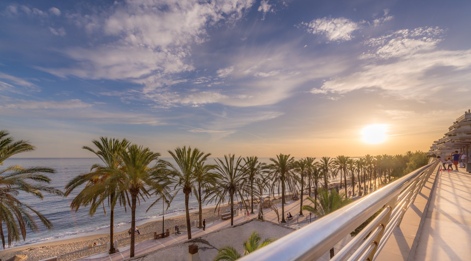 Sunset over the Marbella seafront promenade, palms lining the beach
