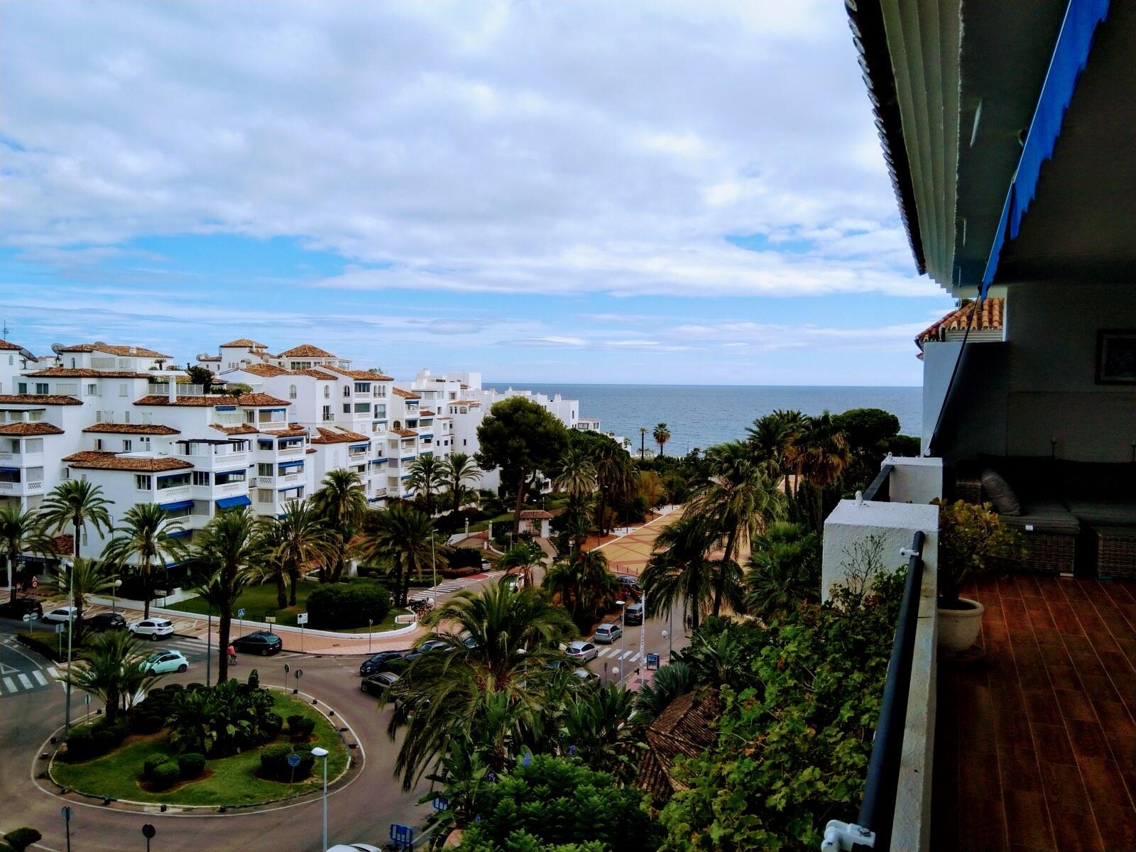 A balcony view over a Nueva Andalucía apartment complex toward the sea